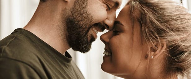 Casal trocando um beijo enquanto seguram presentes de Dia dos Namorados.